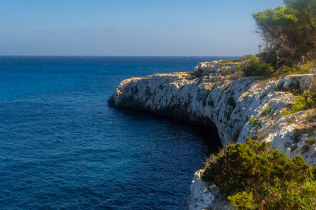 White rocky coast meeting the deep blue sea in a sunny day in Cala Mondrago, Mallorca, Spainの写真素材
