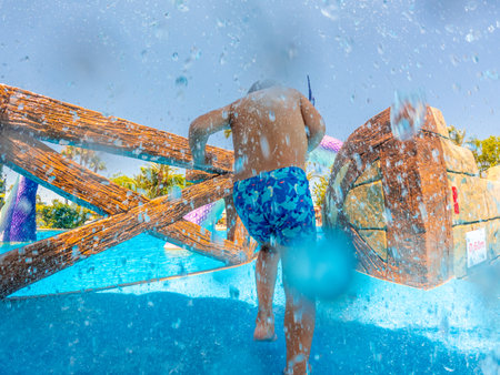 Child joyfully running through playful fountains at a vibrant water park, embracing the excitement and freedom of summer vacationの写真素材