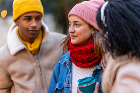 Three friends are chatting and laughing together on a cold winter day in the city, enjoying each other's company and the festive atmosphereの写真素材