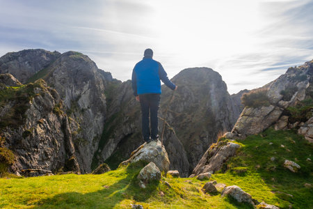 Hiker standing on a rock enjoying the breathtaking landscape of mount penas de aya in oiartzun, a...