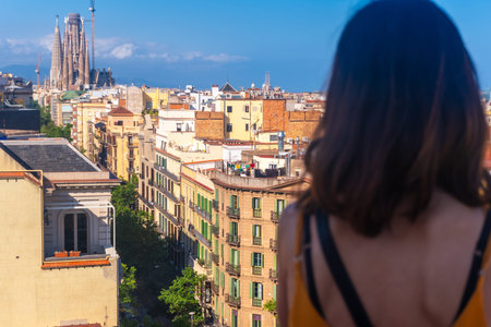 Young woman enjoying panoramic view of Barcelona cityscape, including Sagrada Familia, on a bright...