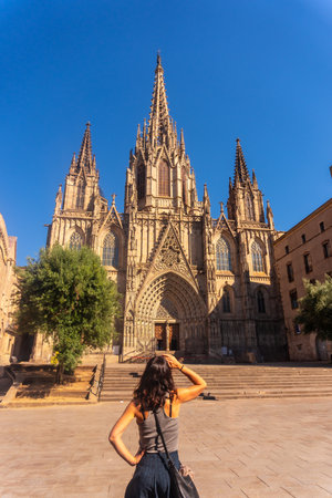 Young woman contemplating the stunning gothic architecture of the Barcelona cathedral on a sunny summer day, embracing the rich cultural heritage of Cataloniaの写真素材