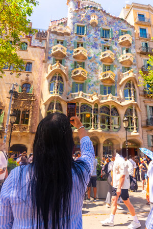 Tourist taking a picture of the colorful facade of Casa Batllo, a UNESCO World Heritage Site in Barcelona, designed by Antoni Gaudiの写真素材