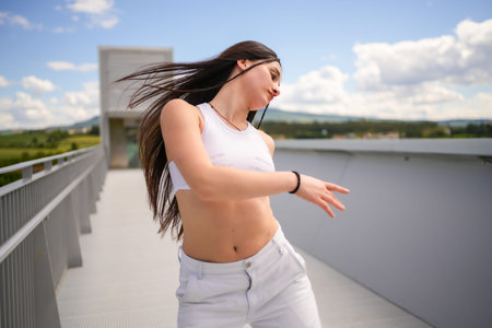 Motion photo of a caucasian young confident young woman dancing urban music on an outdoor bridge