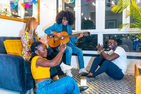 Latin man playing guitar sitting on the sofa with multi-ethnic friends at home at night