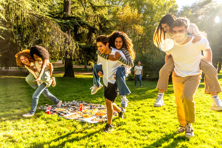 Full length photo of multi-ethnic friends piggybacking and playing games in a park