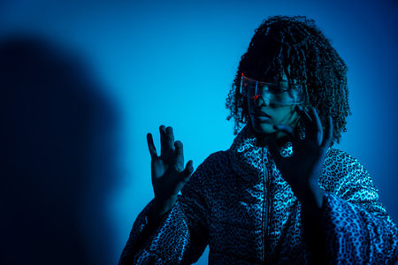 Woman wearing ar headset interacting with virtual reality using hand gestures, illuminated by blue light, futuristic technology conceptの写真素材