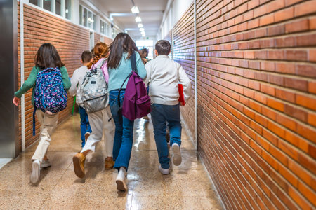 Elementary school students joyfully running down the hallway after the class bell rings, filled with energy and excitement for recessの写真素材