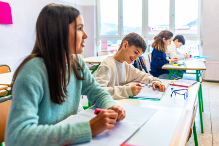 Smiling elementary school students writing on their notebooks during class, learning and education conceptの写真素材