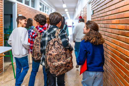 Group of elementary school students walking in the hallway between classes, chatting and carrying backpacksの写真素材