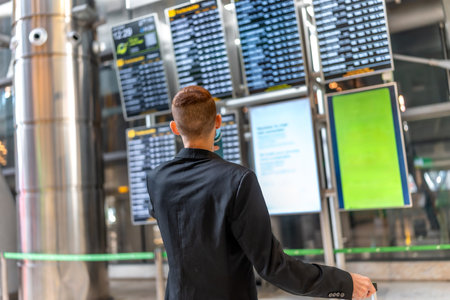 Businessman looking at timetable display while waiting for his flight, travel and business conceptの写真素材