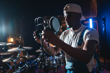 Young african american artist adjusting microphone, preparing to record a new album in a music studioの写真素材