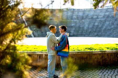 Two young men embracing in a sunlit park, celebrating love, acceptance, and the vibrant spirit of lgbtq plus rights and communityの写真素材