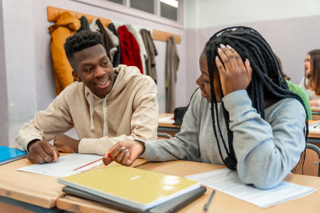 Two high school students working together on a project, sharing ideas and collaborating in a classroom settingの写真素材