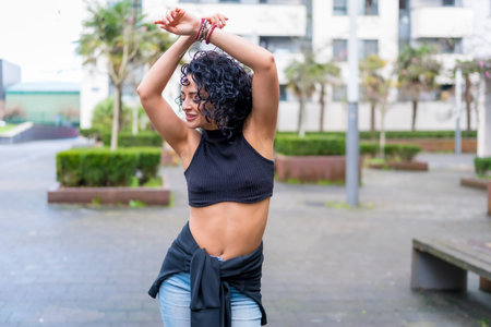 Young woman dancing in urban park, enjoying freedom and expressing herself through modern dance...