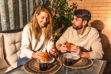 Happy couple enjoying burgers and wine on a cozy terrace, creating a romantic and intimate atmosphereの写真素材