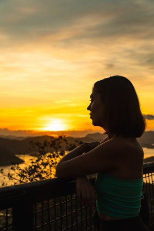 Silhouette of young woman enjoying golden sunset over coron island at mount tapyas viewpoint in philippinesの写真素材
