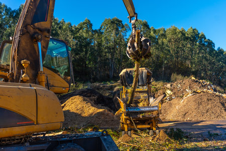 Side view of an excavator transporting waste outside a recycling plant in a sunny dayの写真素材