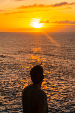 Silhouette of tourist contemplating beautiful golden sunset over Atlantic ocean in Agaete, Gran...