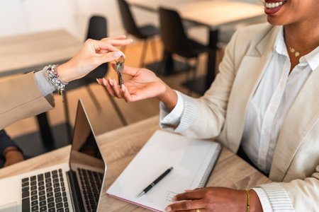 Real estate agent handing over keys to a new homeowner, symbolizing a successful property purchaseの写真素材