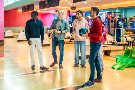 Group of multi ethnic friends wearing casual clothes having fun bowling together at the bowling...