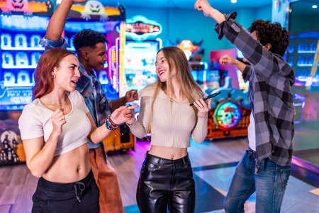 Four young multiethnic friends are enjoying their weekend together, playing arcade games, dancing, and having fun in a vibrant entertainment centerの写真素材