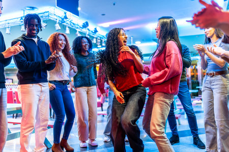 Young multiethnic friends are dancing and having fun together at a bowling alley, enjoying the weekend vibesの写真素材