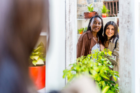 Two women are smiling and choosing plants in a gardening store, enjoying their shopping experience togetherの写真素材