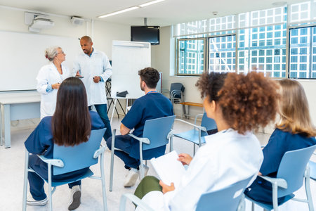 Doctors and nurses listening to senior colleagues giving presentation during medical conference in...