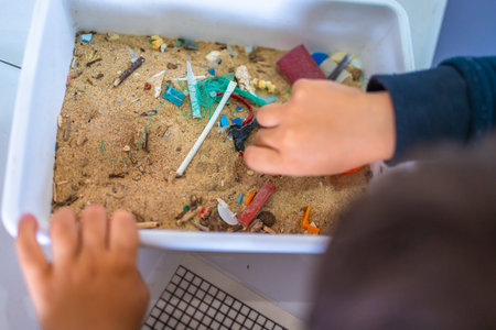 Young student analyzing a sand sample containing microplastics, highlighting the growing concern of...