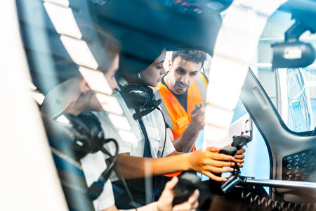 Instructor explaining aircraft controls to two pilot students during flight training inside cockpit...