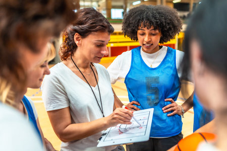 Basketball coach explaining game strategy to her team using whiteboard, during training in the court