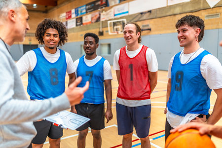 Coach holding clipboard explaining game strategy to his basketball team players wearing training bibsの写真素材