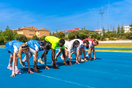 Diverse group of athletes ready to start a race on a blue running track, embodying competition and athleticismの写真素材