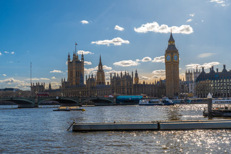 Westminster palace with big ben and westminster bridge over river thames under a blue sky in london,...