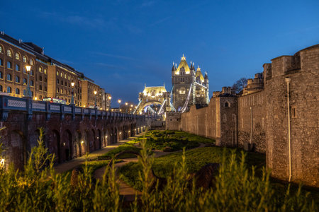 Tower bridge and the tower of London stand majestically illuminated against the twilight sky,...