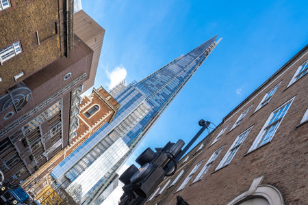 Low angle view of the shard skyscraper dominating the skyline above traditional brick buildings in London, UK, highlighting the contrast between old and newの写真素材