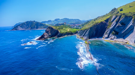 Breathtaking aerial view of the unique flysch cliffs meeting the deep blue water of the Cantabrian sea on a sunny summer day in Zumaia, Gipuzkoaの写真素材
