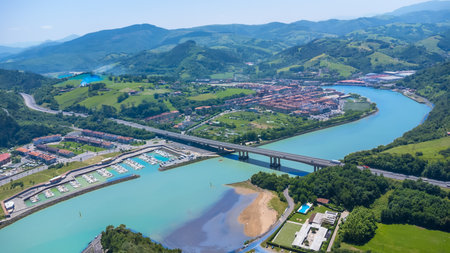 Aerial view of Orio, a charming town in Gipuzkoa, Basque Country, Spain, showing the river, bridge, marina, and surrounding landscape on a sunny summer dayの写真素材