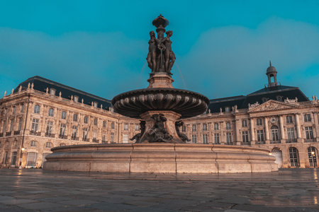 The fountain of the three graces graces place de la bourse in bordeaux, france, illuminated by the soft glow of twilightの写真素材