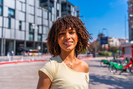Smiling young woman enjoying a sunny summer day in a vibrant urban setting, surrounded by modern architecture and cheerful energyの写真素材