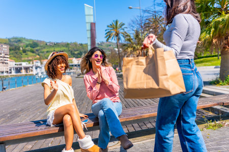 Three happy women enjoying sunny day in a city with palm trees and waterfront view, having fun togetherの写真素材