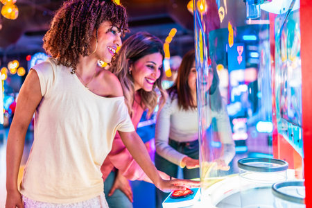 Three friends enjoying their time together playing an arcade game in a colorful entertainment venueの写真素材