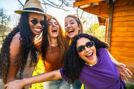 Four multi ethnic female friends are having fun together in a park, laughing and enjoying each other's companyの写真素材