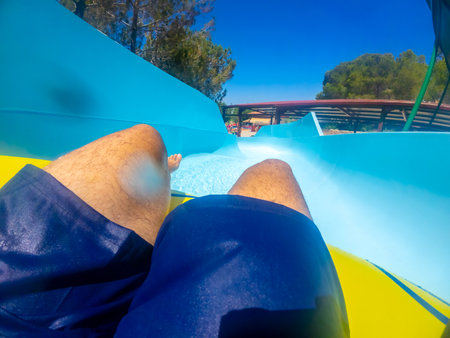 Point of view of a man sliding down a thrilling waterslide at an aquatic park, enjoying summer holidays filled with fun and excitementの写真素材