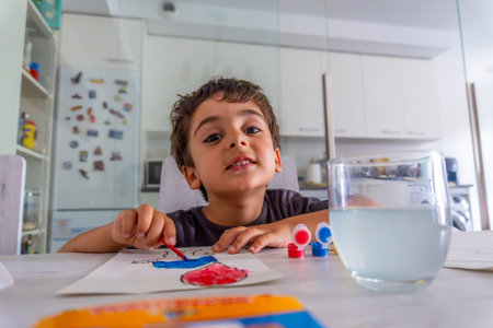 Young boy painting with vibrant watercolors at the kitchen table, fully immersed in his creative expression and enjoying every momentの写真素材