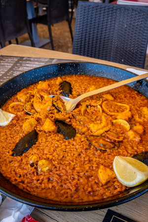 Steaming paella with mussels, shrimp, and calamari, served in a traditional bread and garnished with lemon, ready to be enjoyedの写真素材