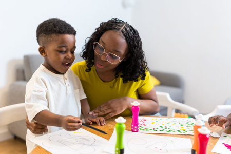 Young mother helps her son with painting, fostering creativity and strengthening their bond in a...