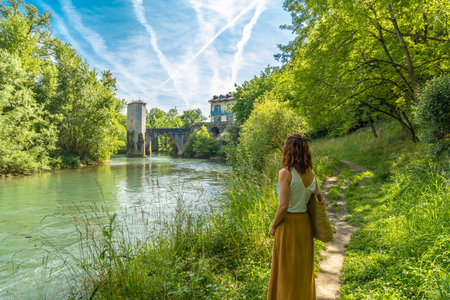 Woman enjoying summer vacations in french countryside admiring the medieval bridge and tower of...