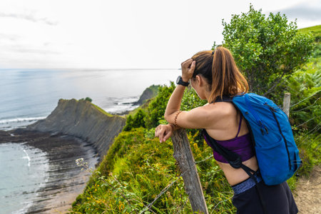 Female hiker enjoying the scenic view of the Sakoneta beach and its coastal flysch in Zumaia,...